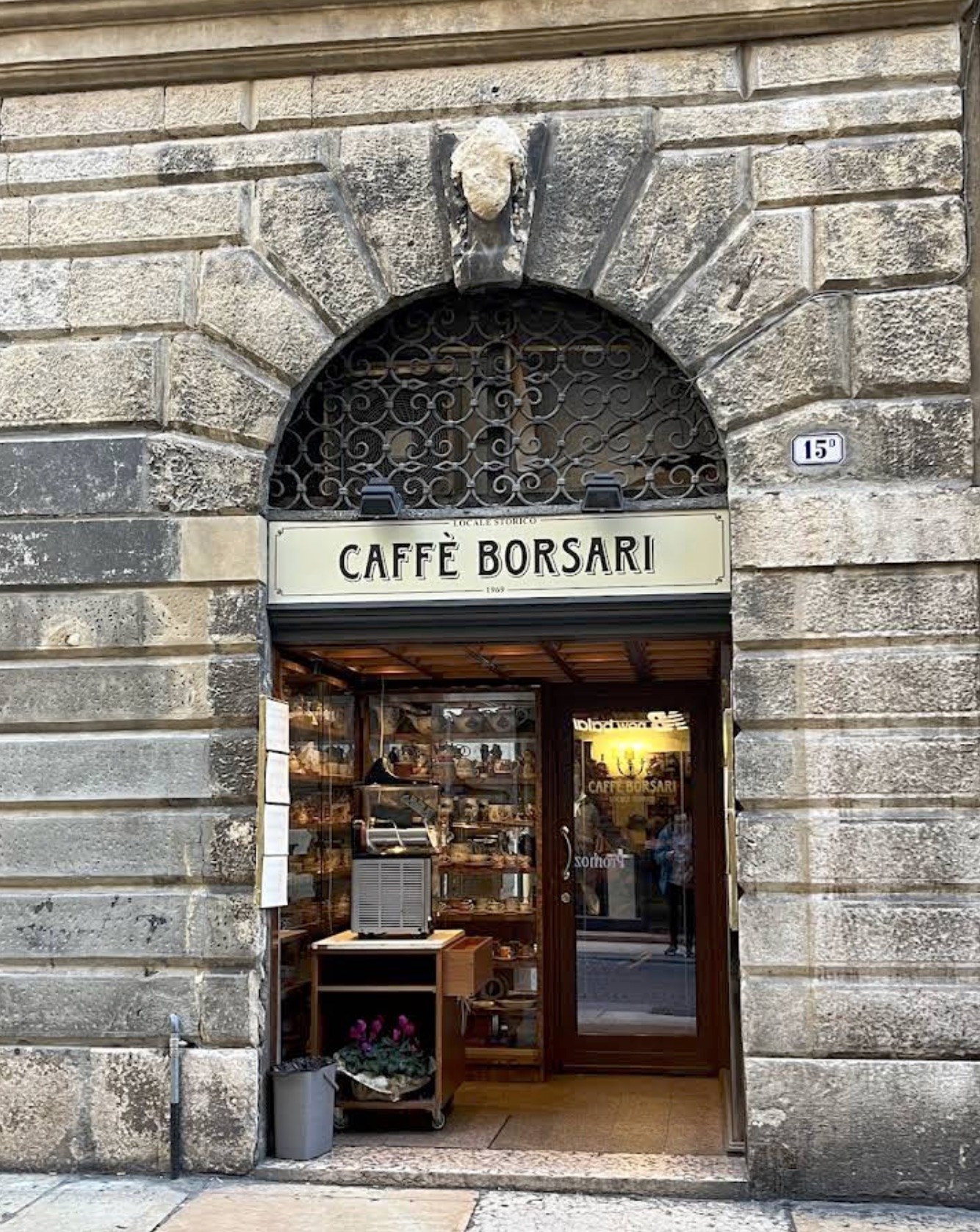 A stone archway entrance with the Caffè Borsari sign above the door and the lit interior visible through the glass