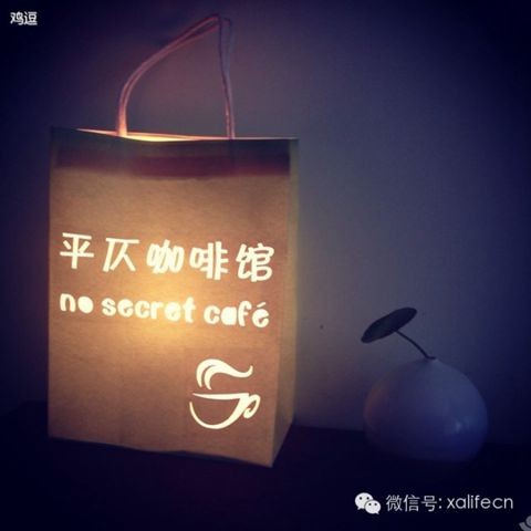A candlelit paper takeaway bag printed with the Pingze Coffee logo and the tagline no secret cafe