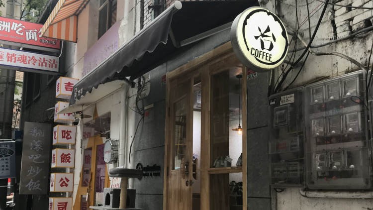 The shop's round backlit sign reading Ye Coffee above a wooden framed entrance with a hanging pendant light