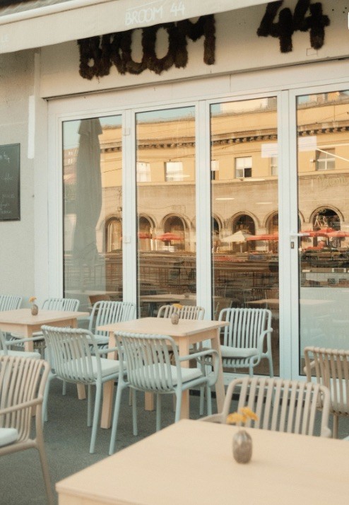 Outdoor tables and chairs beneath the Broom 44 awning, with Dolac market reflected in the glass doors