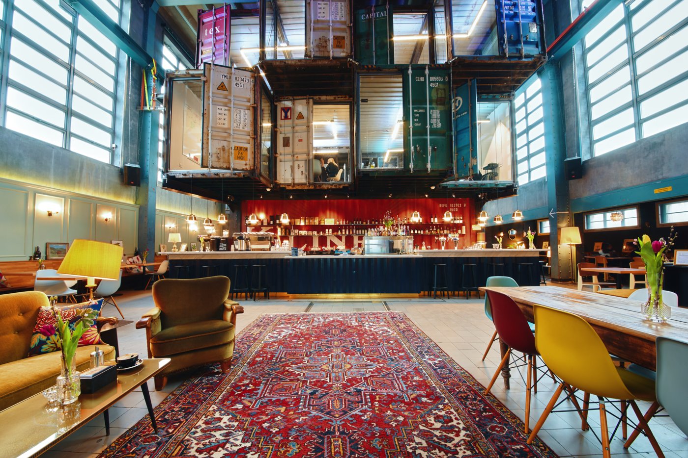 Kraftwerk's cavernous former power-station hall, a bar beneath stacked shipping-container work pods and a long red rug